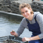 Virginia aquaculture oyster grower with a basket of mature oysters.